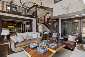 Living area featuring stairway, a towering ceiling, dark wood finished floors, and a chandelier