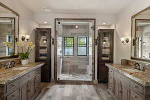 Bathroom with a shower stall, two vanities, recessed lighting, and light wood finished floors