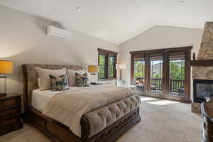 Bedroom with carpet flooring, access to outside, a wall mounted air conditioner, a fireplace, and high vaulted ceiling