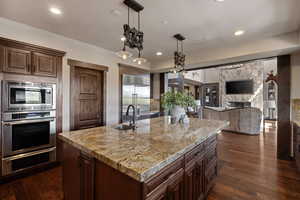 Kitchen featuring hanging light fixtures, dark brown cabinets, built in appliances, dark wood-style floors, and recessed lighting