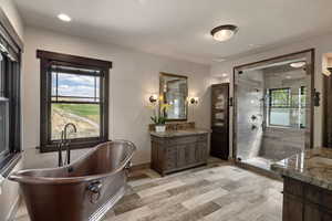 Full bathroom featuring vanity, a freestanding bath, a stall shower, and recessed lighting