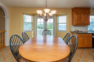 Dining room featuring plenty of natural light, arched walkways, a chandelier, and light flooring