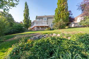 View of green lawn featuring stairway and a wooden deck