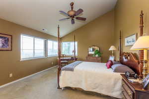 Carpeted bedroom with a ceiling fan and high vaulted ceiling