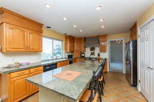 Kitchen featuring a kitchen island, appliances with stainless steel finishes, a breakfast bar, premium range hood, and recessed lighting