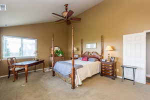 Bedroom with light carpet, high vaulted ceiling, and ceiling fan