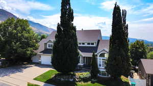 View of front of property with a mountain view, concrete driveway, a shingled roof, and a garage