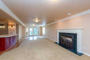 Unfurnished living room with french doors, ornamental molding, a tile fireplace, a textured ceiling, and light wood-style flooring