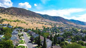 Aerial view of property and surrounding area featuring mountains and nearby suburban area