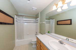 Full bath with shower / bath combo with shower curtain, vanity, and a chandelier