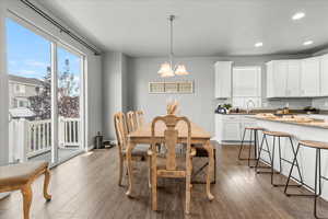 Dining area with a chandelier, dark wood-style floors, and recessed lighting