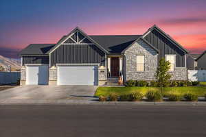 View of front of house featuring board and batten siding, stone siding, concrete driveway, and an attached garage