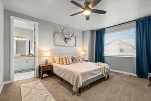 Bedroom featuring light carpet, ceiling fan, and ensuite bath