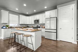 Kitchen featuring stainless steel appliances, a breakfast bar area, white cabinets, and recessed lighting
