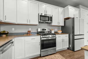 Kitchen featuring stainless steel appliances, dark wood-style flooring, and white cabinetry