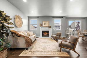 Living room featuring plenty of natural light, a lit fireplace, dark wood finished floors, and recessed lighting