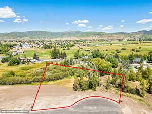 Aerial overview of property's location featuring a mountainous background and property boundaries highlighted