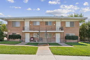 View of front of property featuring stairway, brick siding, and a balcony