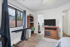 Bedroom with light colored carpet, a ceiling fan, and ensuite bath