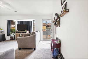 Living area featuring carpet, tile patterned floors, and ceiling fan