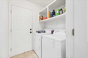 Laundry room with light tile patterned flooring and washing machine and dryer