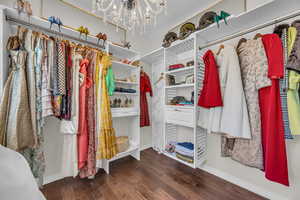 Walk in closet featuring dark wood finished floors and a chandelier