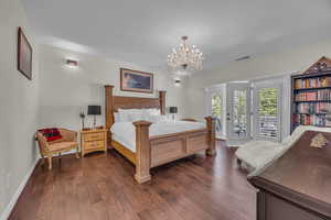 Bedroom featuring dark wood-type flooring, a chandelier, and access to outside