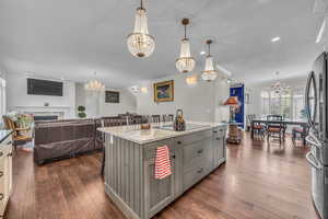 Kitchen featuring a chandelier, light stone countertops, open floor plan, freestanding refrigerator, and recessed lighting