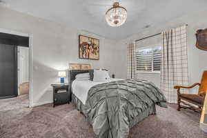 Carpeted bedroom featuring a chandelier and baseboards