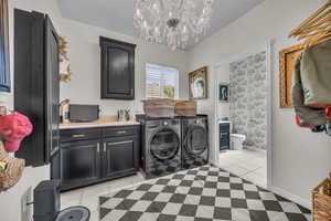 Laundry room featuring light tile patterned floors, washer and dryer, and a chandelier