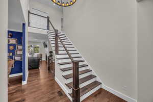 Staircase with a towering ceiling and wood finished floors