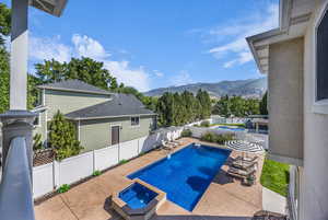 View of pool with a patio area, a fenced backyard, a pool with connected hot tub, and a mountain view