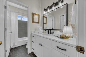 Full bathroom with vanity, shower / tub combo with curtain, and dark tile patterned flooring