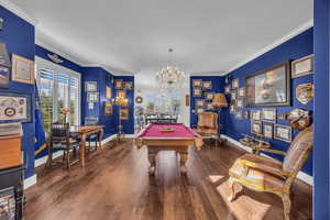 Playroom with crown molding, billiards, dark wood-style flooring, and a chandelier