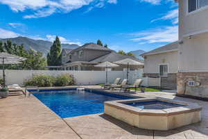 View of pool with a mountain view, a patio, an in-ground hot tub, and a fenced backyard