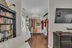 Walk in closet featuring dark wood-style flooring and a chandelier