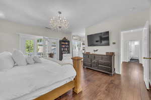 Bedroom featuring dark wood finished floors, access to outside, and a chandelier