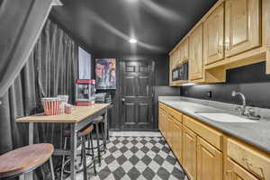 Kitchen with black microwave, light brown cabinetry, light floors, and recessed lighting