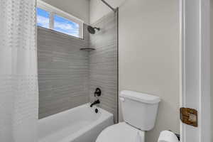 Full bath with shower / bath combo with shower curtain and toilet