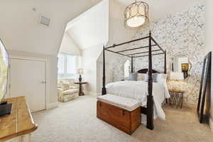 Bedroom with wallpapered walls, light colored carpet, and a high ceiling