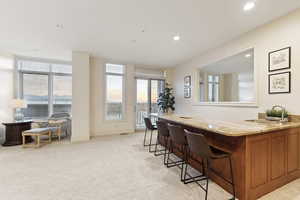 Bar area with light carpet, recessed lighting, and light stone countertops