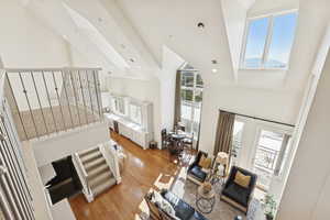Living room with high vaulted ceiling, light wood-type flooring, a skylight, and recessed lighting