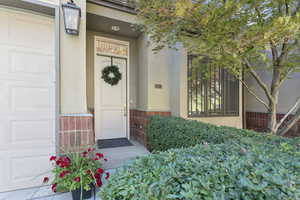 Doorway to property featuring stucco siding, brick siding, and a garage