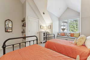 Bedroom with light colored carpet and high vaulted ceiling