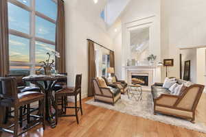 Living area with light wood-style floors, high vaulted ceiling, a fireplace, and recessed lighting