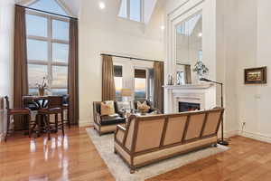 Living room with light wood-type flooring, a high ceiling, a glass covered fireplace, and recessed lighting