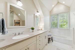 Bathroom with double vanity, light tile patterned flooring, a bath, vaulted ceiling, and recessed lighting