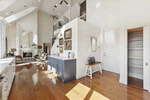 Kitchen featuring high vaulted ceiling, dark wood finished floors, a fireplace, a ceiling fan, and light stone countertops