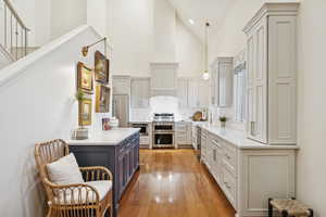 Kitchen with high vaulted ceiling, decorative light fixtures, light stone counters, tasteful backsplash, and appliances with stainless steel finishes