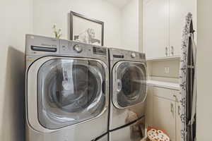 Washroom with cabinet space and washing machine and clothes dryer